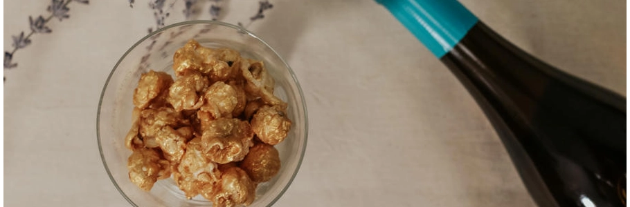 Copa con palomitas gourmet Popit junto a una botella de vino: propuesta de maridaje