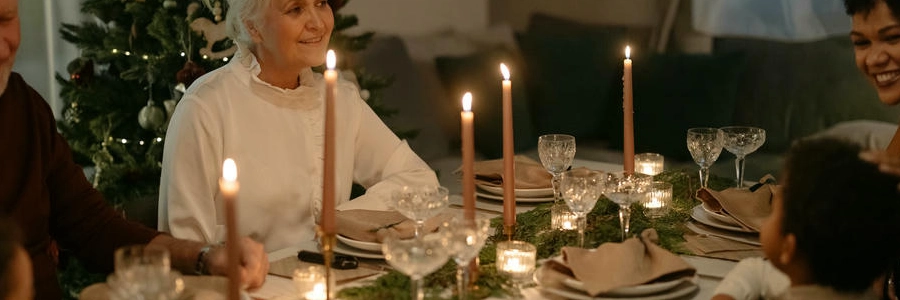 Abuela sonriendo en una cena familiar navideña con velas encendidas y mesa decorada